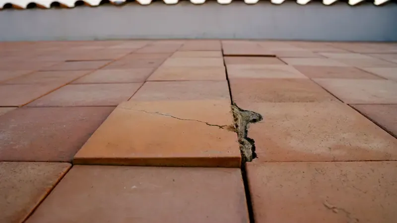 Cracked floor tile on a terrace with a broken gap along the joint